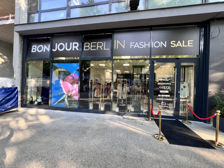 ußenansicht des Bonjour Berlin High Fashion Geschäfts. Die stilvolle Fassade und das ansprechende Schaufenster präsentieren exklusive Mode von Dolce & Gabbana. Das moderne Design des Eingangsbereichs zieht die Aufmerksamkeit der Passanten auf sich.