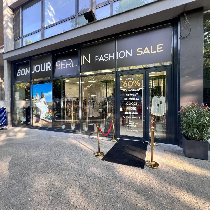 Marken Outlet – Außenansicht unserer Modefensterfront Außenansicht des Bonjour Berlin High Fashion Geschäfts. Die moderne Fassade mit großen Fenstern präsentiert stilvoll die exklusive Dolce & Gabbana Mode. Das elegante Schaufenster zieht die Blicke der Passanten auf sich und lädt zum Eintreten ein.